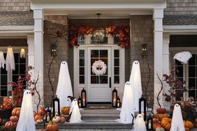 A house decorated for Halloween with ghost figures pumpkins and lights on the front porch