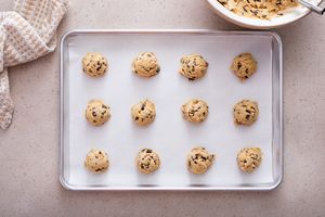 Chocolate chip cookie dough scooped on a cookie sheet ready to be baked. 