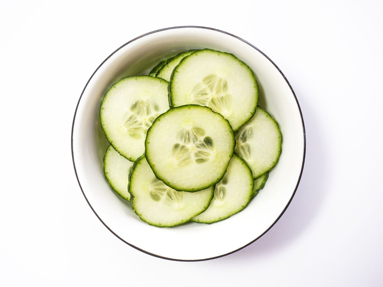 Sliced cucumbers in a white bowl. 