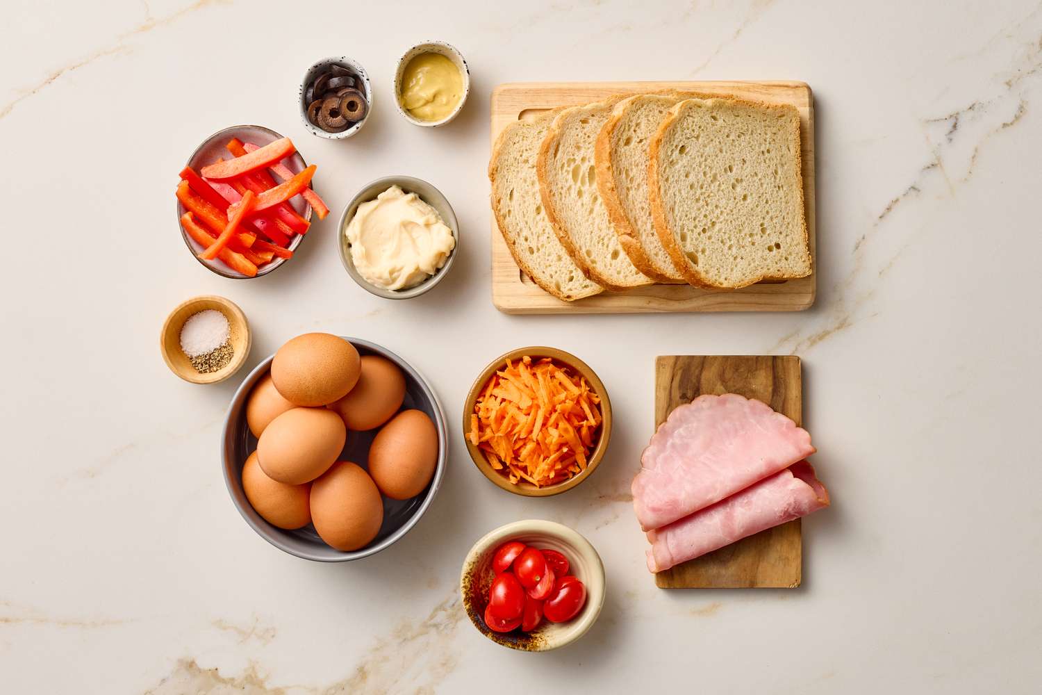 Openface sandwich ingredients including bread ham eggs grated carrot sliced peppers cherry tomatoes mayonnaise mustard and spices