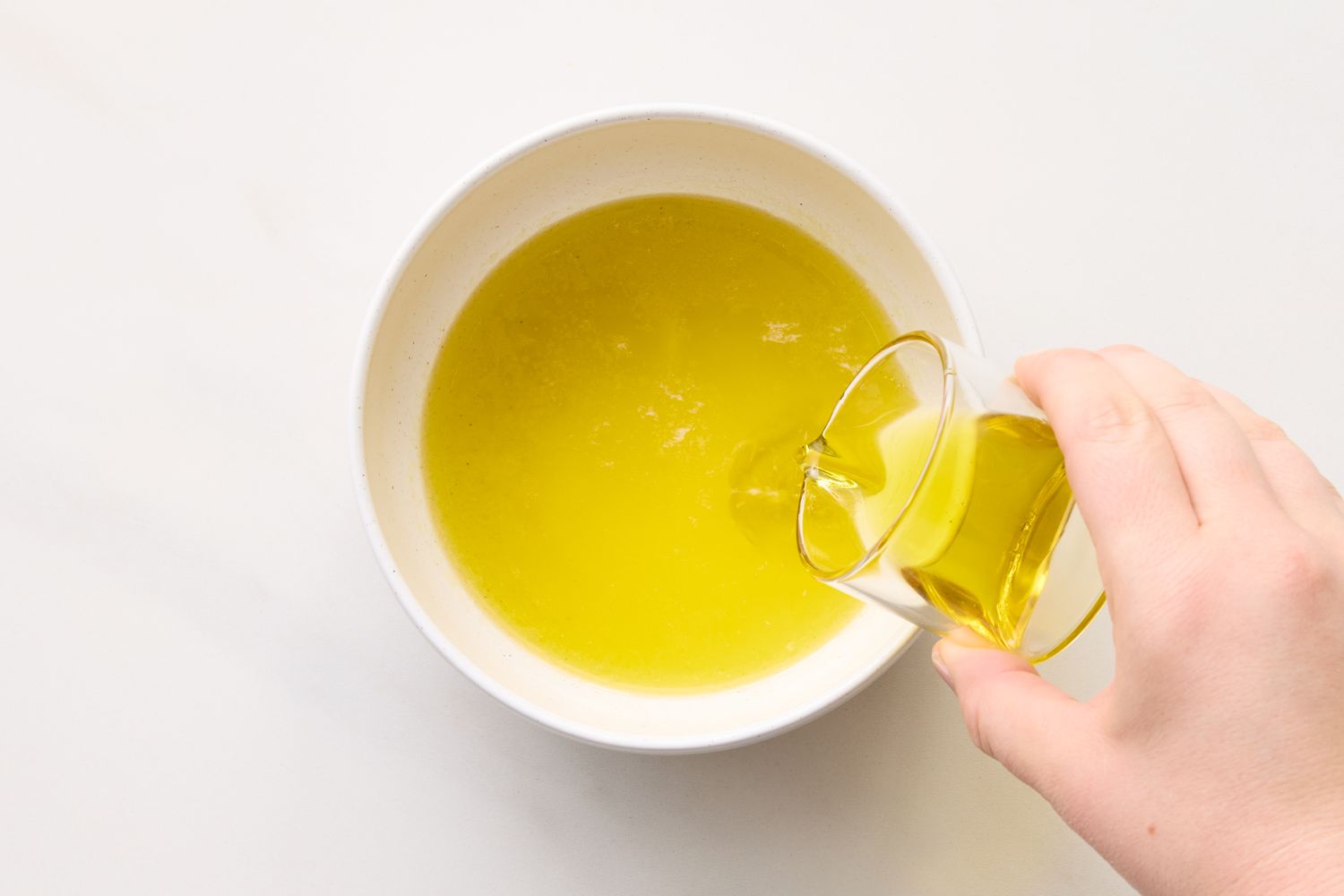 A hand pouring oil into a bowl