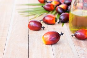red palm kernels and a bottle of palm oil on light wood surface