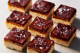 Chocolatetopped caramel cookie bars with a sprinkle of sea salt arranged in a grid format