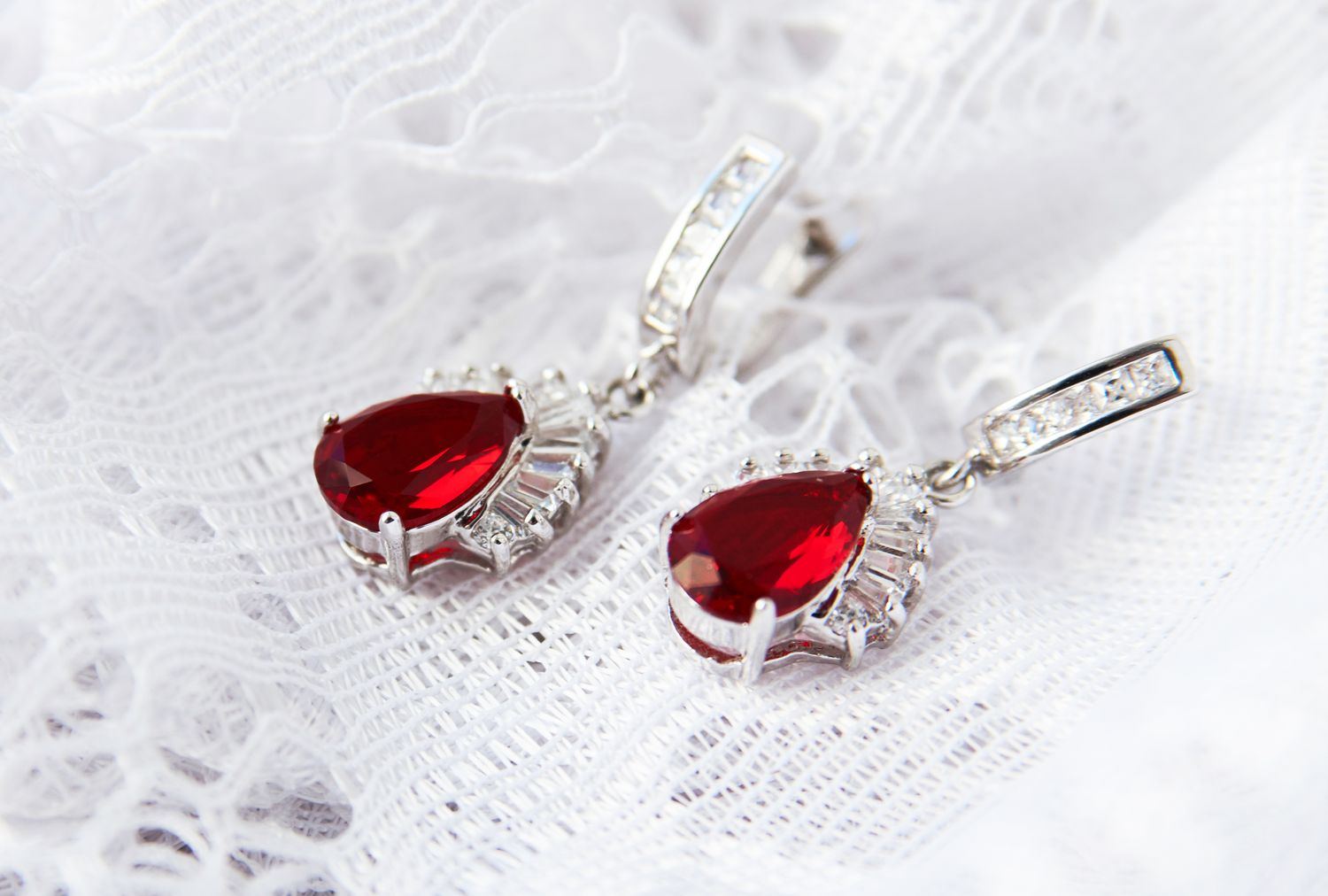 A pair of ruby drop earrings on a lace background