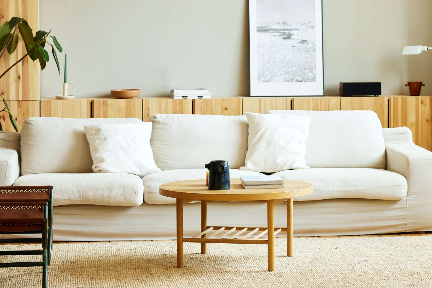 A living room setup with a beige sofa light wooden coffee table and wall art