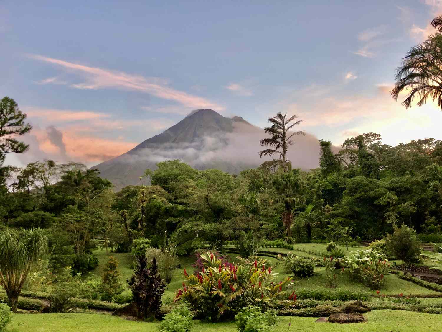 A scenic view of a mountain surrounded by lush greenery and gardens