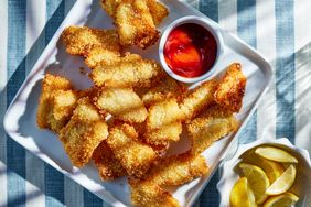panko breaded fish sticks on a platter with dipping sauce and lemon wedges