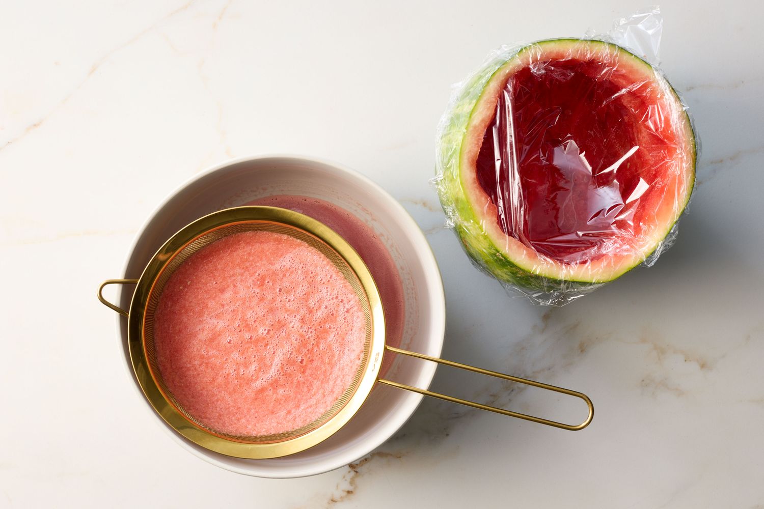 Preparation of watermelon punch, a sieve with juice and a watermelon half covered in plastic wrap