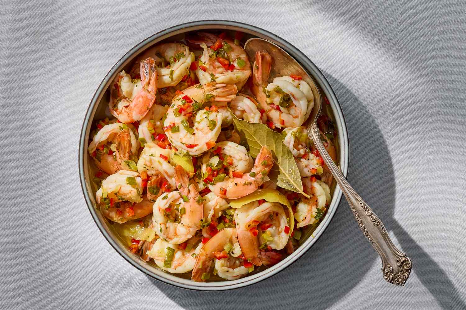 A dish of marinated shrimp with pickled lemon and chiles served with a decorative spoon