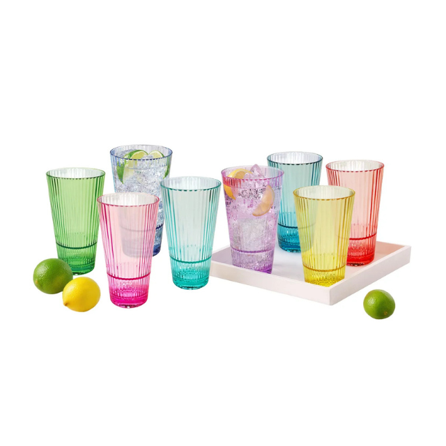 A set of colorful drinking glasses with a tray and limes scattered around