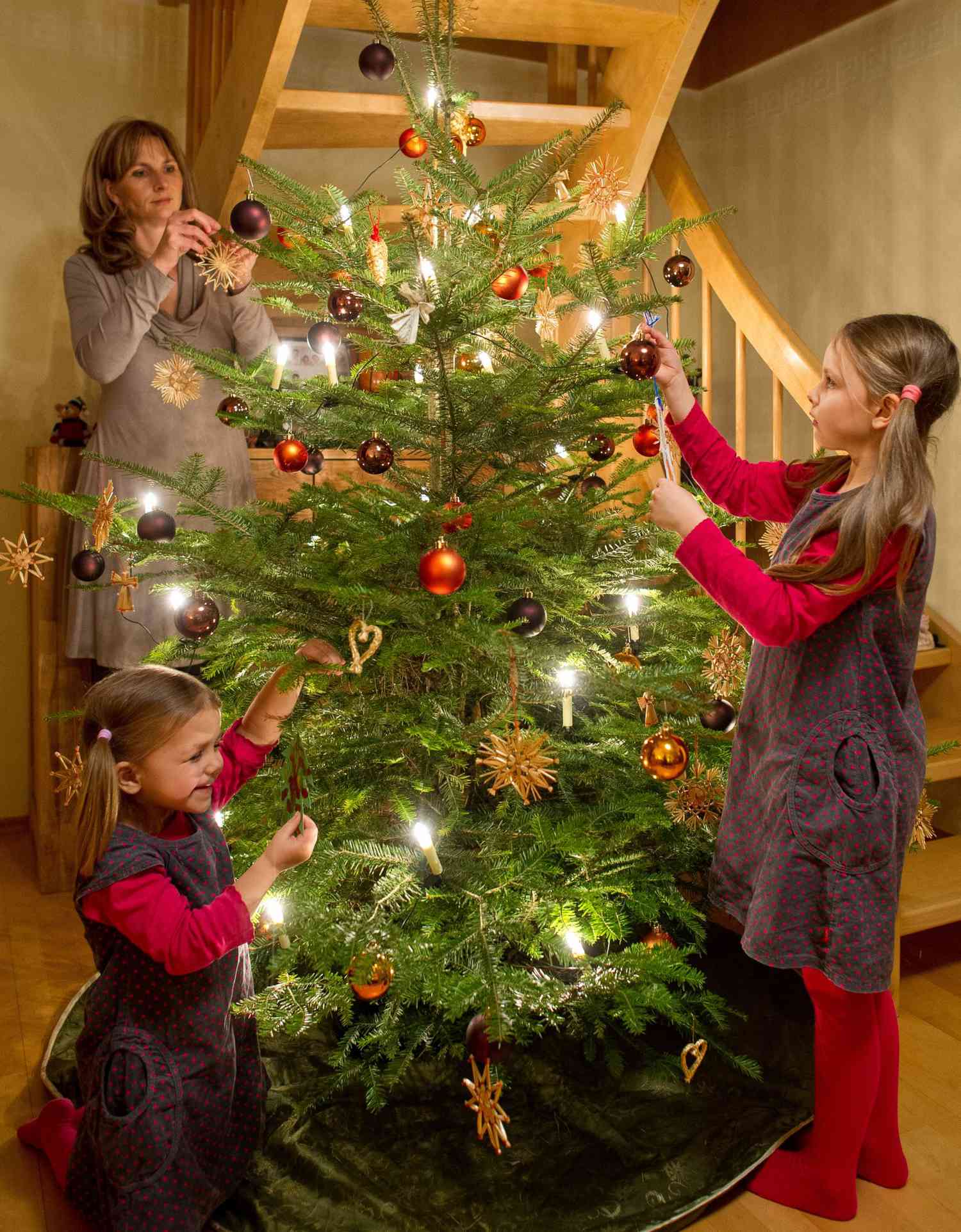 mother and daughters decorate the Christmas tree