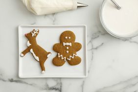 overhead view of two gingerbread cookies and frosting bowl