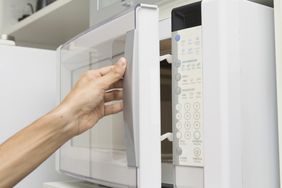 Hand opening a microwave oven