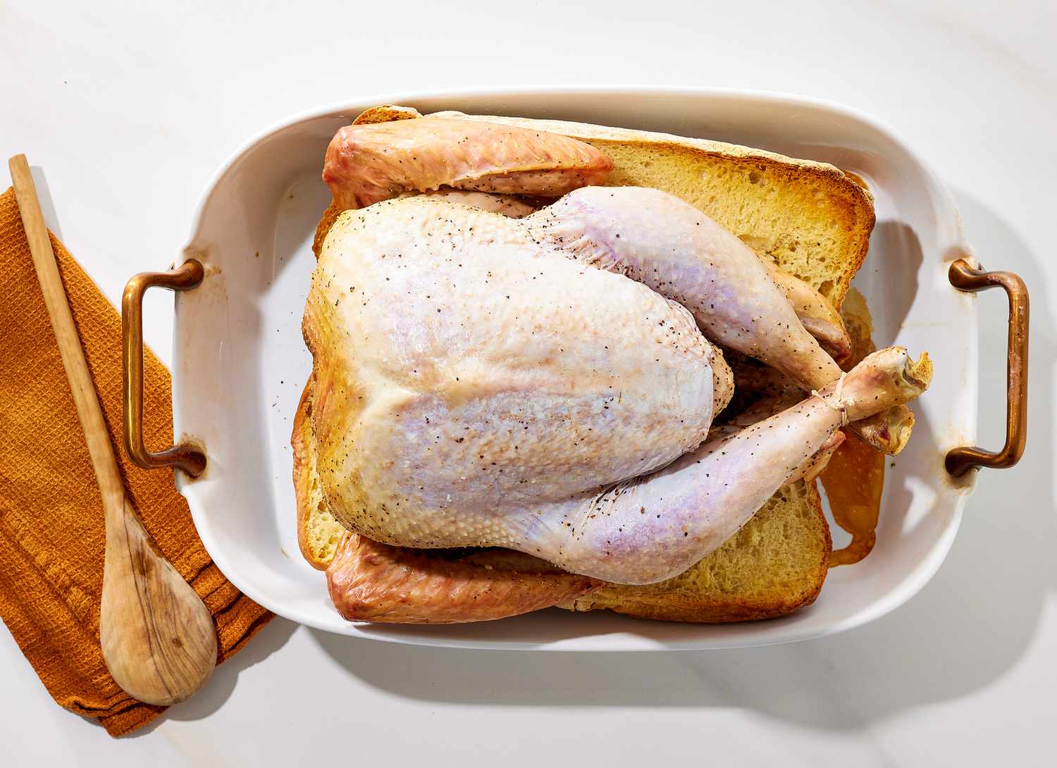overhead view of raw turkey in a casserole dish with bread