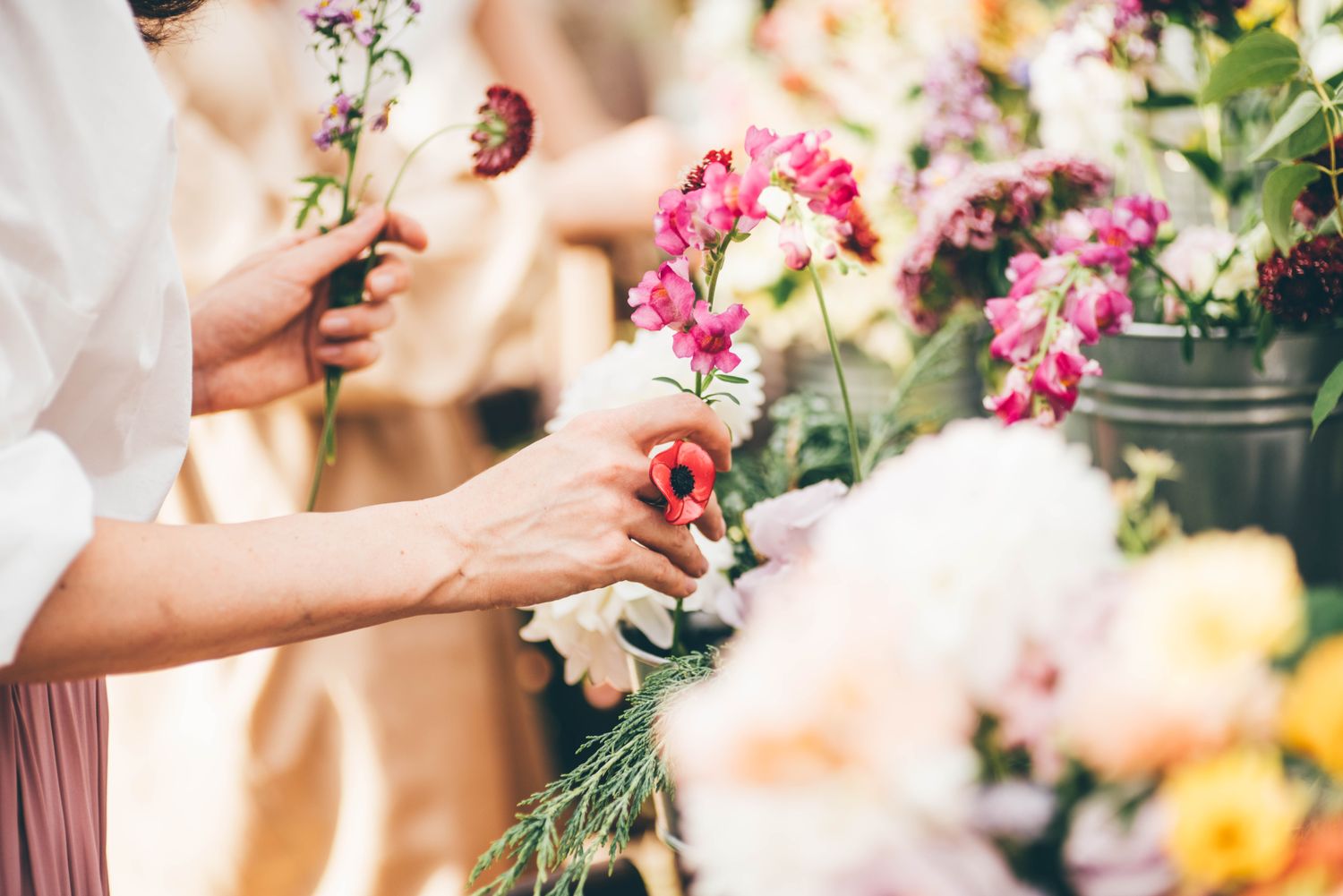 Hands arranging flowers at a market or shop with colorful blooms in focus