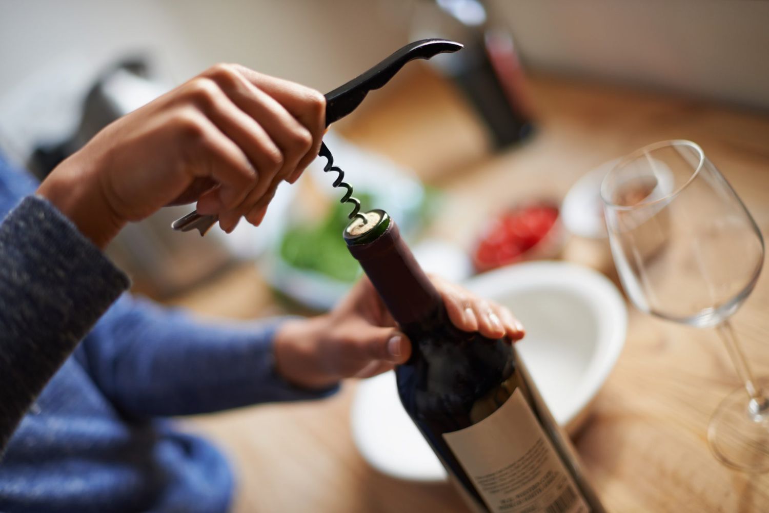 opening a wine bottle using a corkscrew