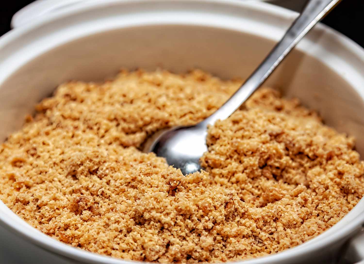 close up view of light brown sugar in white bowl with a spoon 