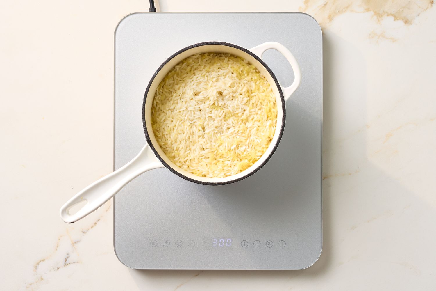 A saucepan containing cooked rice rests on an induction cooktop