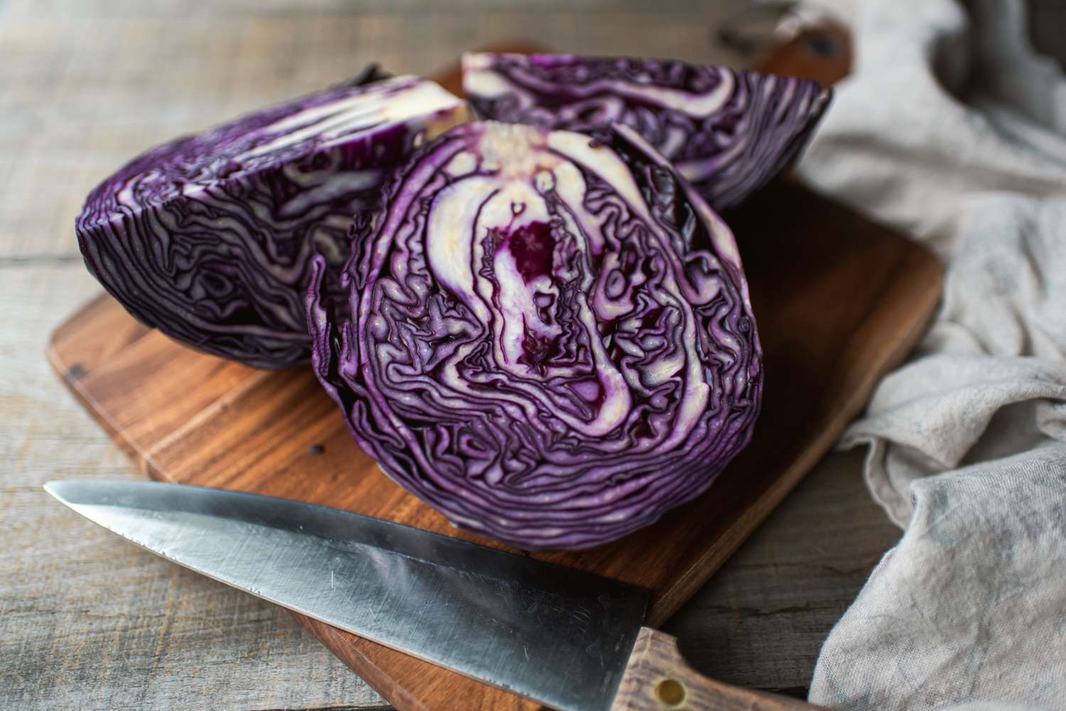 Sliced red cabbage on a wooden cutting board with a knife nearby