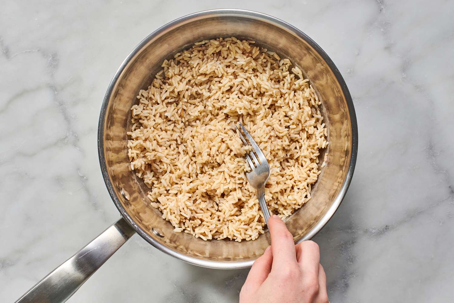 fluffing cooked brown rice with a fork
