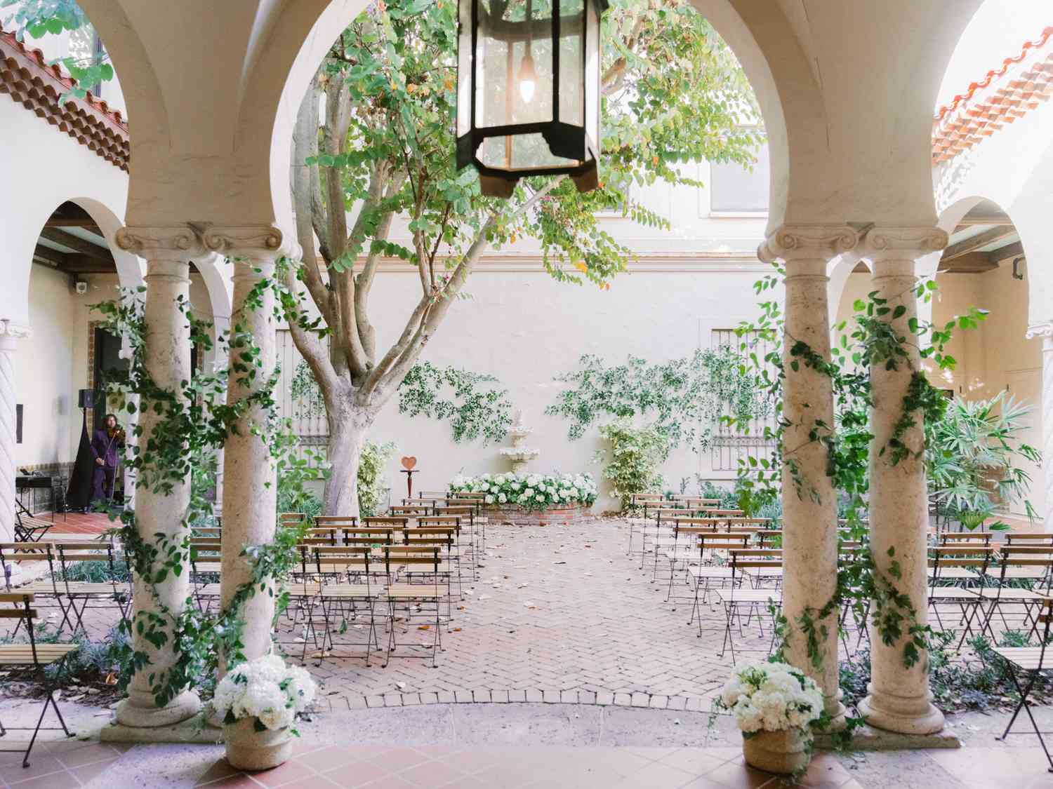 outdoor ceremony set up in courtyard with floral altar and violinist