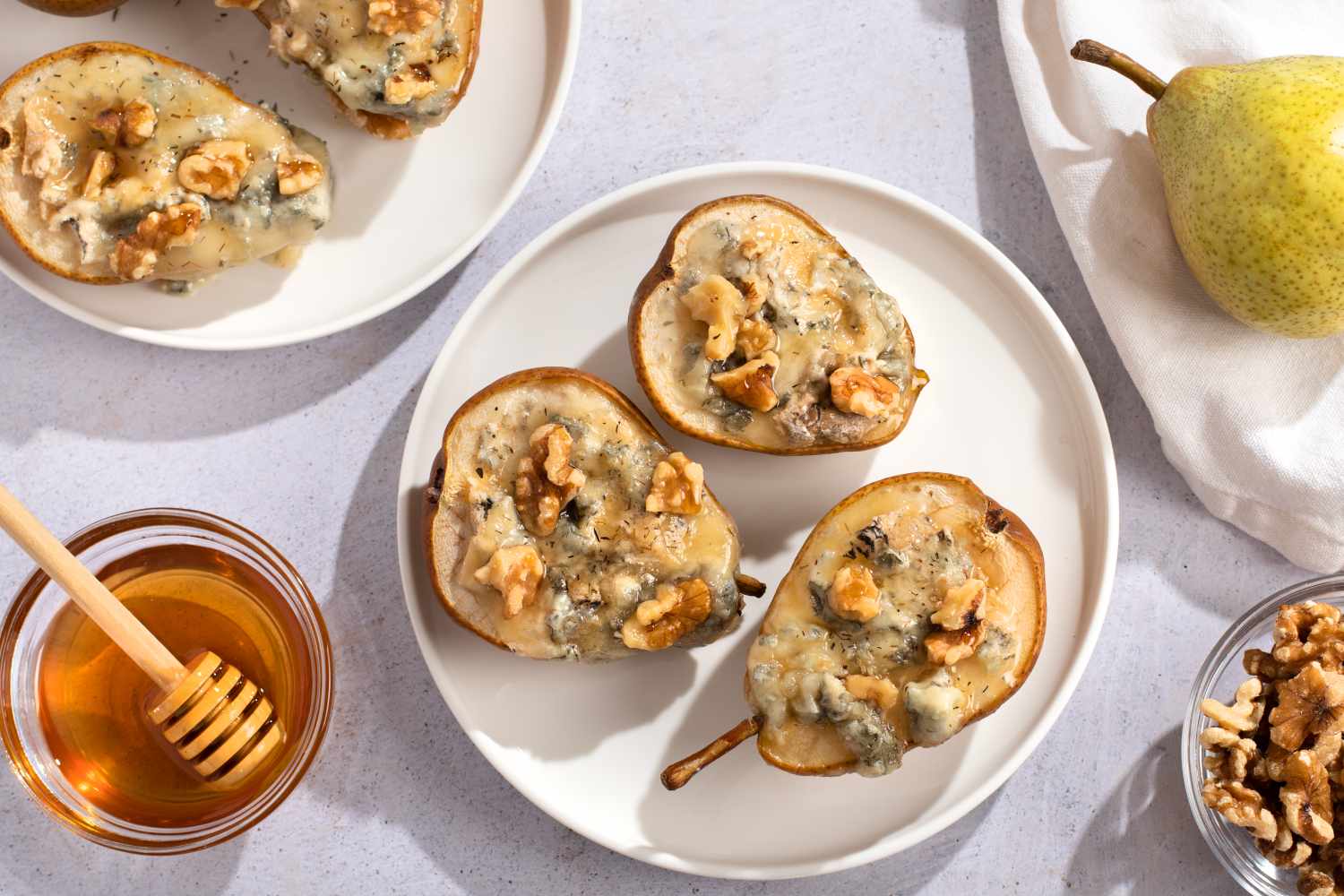 Baked pears with blue cheese, walnuts and honey on white plate closeup,