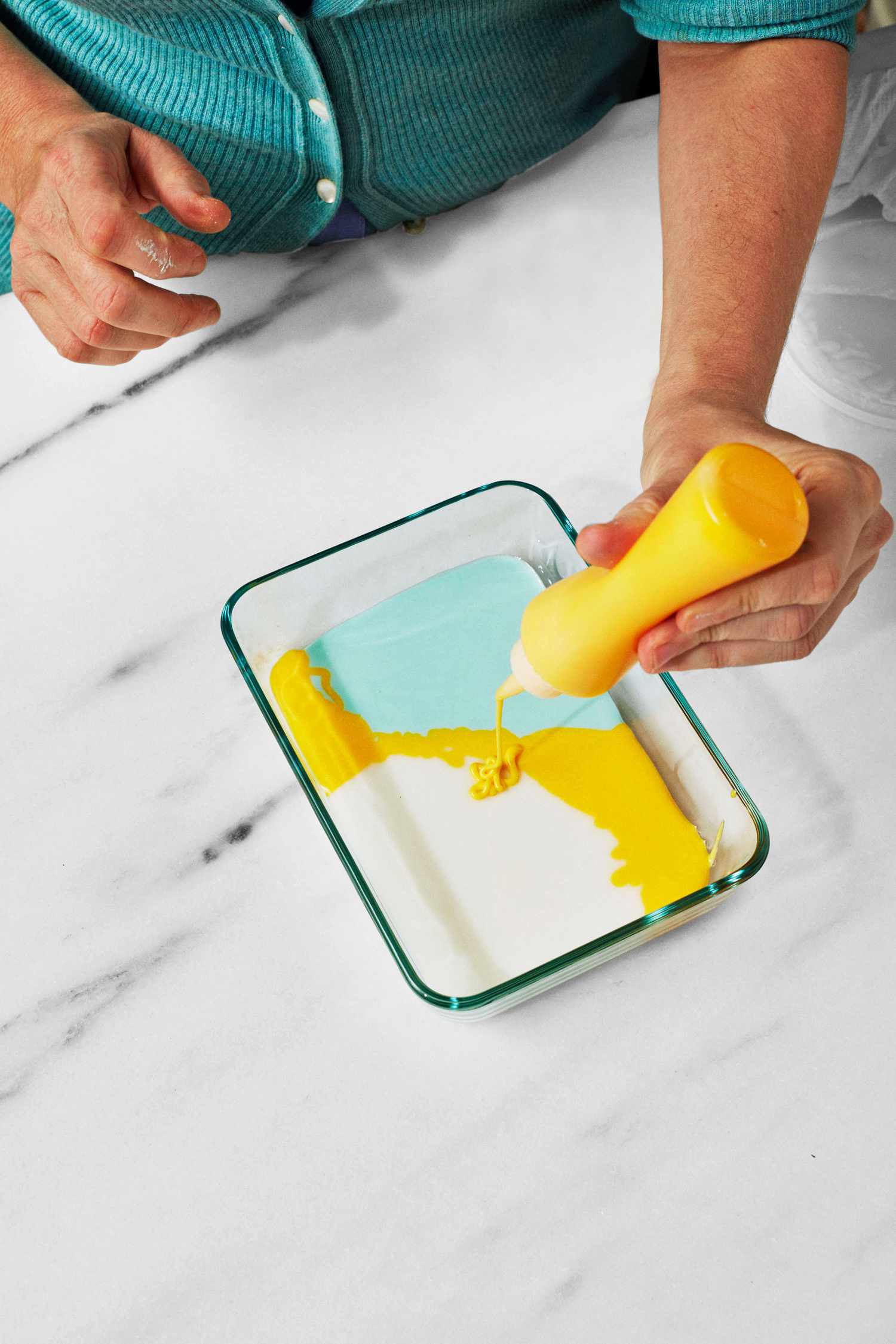 martha pouring yellow frosting into pyrex to make tie dye cookies