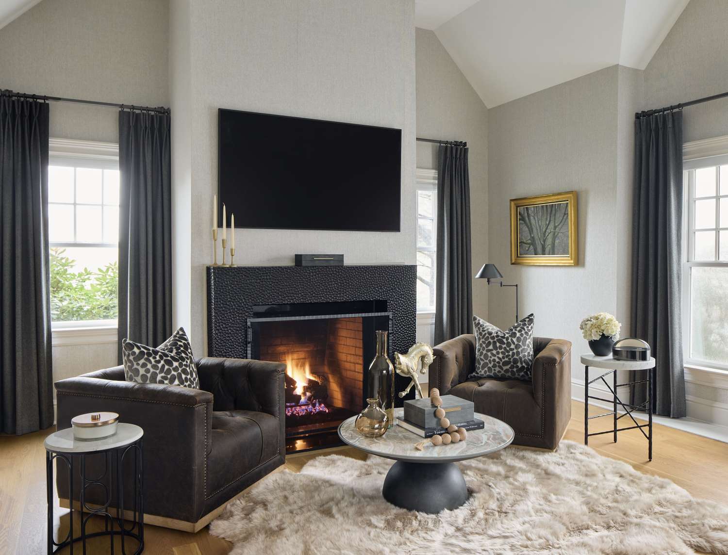 Living room with two chairs by a fireplace a television mounted above and a modern decor style