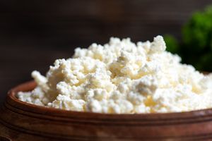 A wooden bowl filled with cottage cheese closeup view