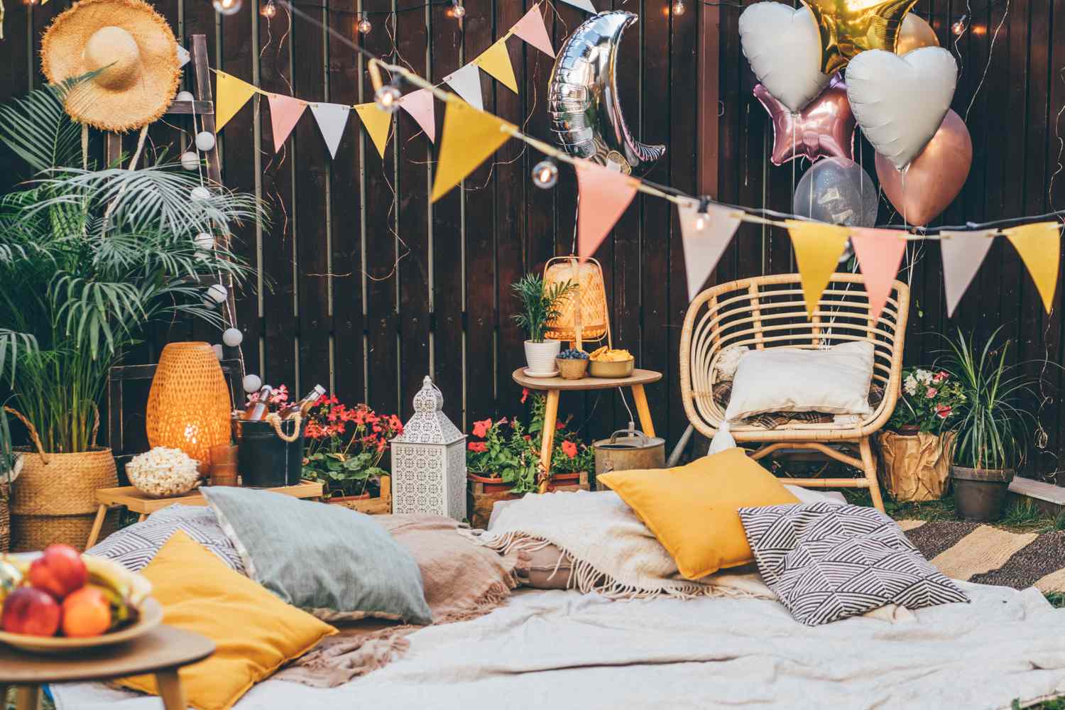 Outdoor seating area with cushions bunting balloons and decorations creating a festive and cozy atmosphere