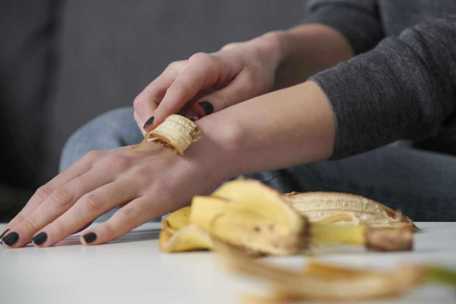 Woman rubbing banana peel on her hands to hydrate skin