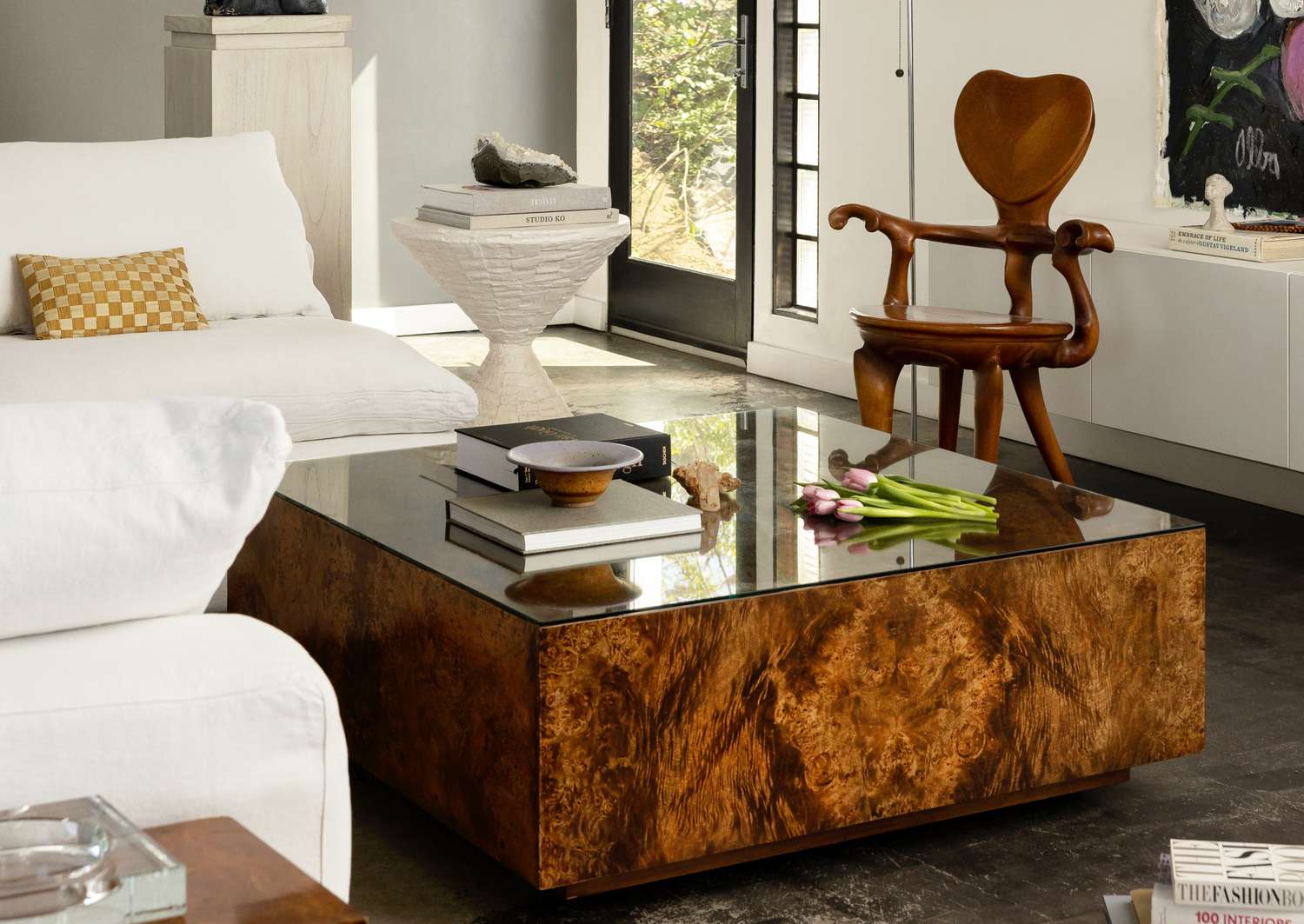 A living room interior with a burl wood coffee table modern furnishings and artistic decor
