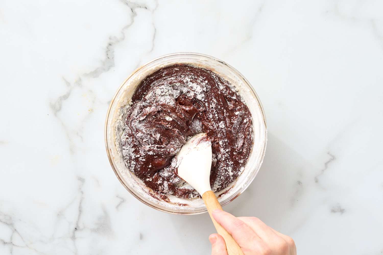 Bowl of brownie batter being mixed with a spatula
