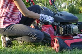 Person starting a lawnmower outdoors
