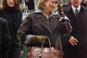 decorvow walking outside holding a Birkin bag accompanied by others