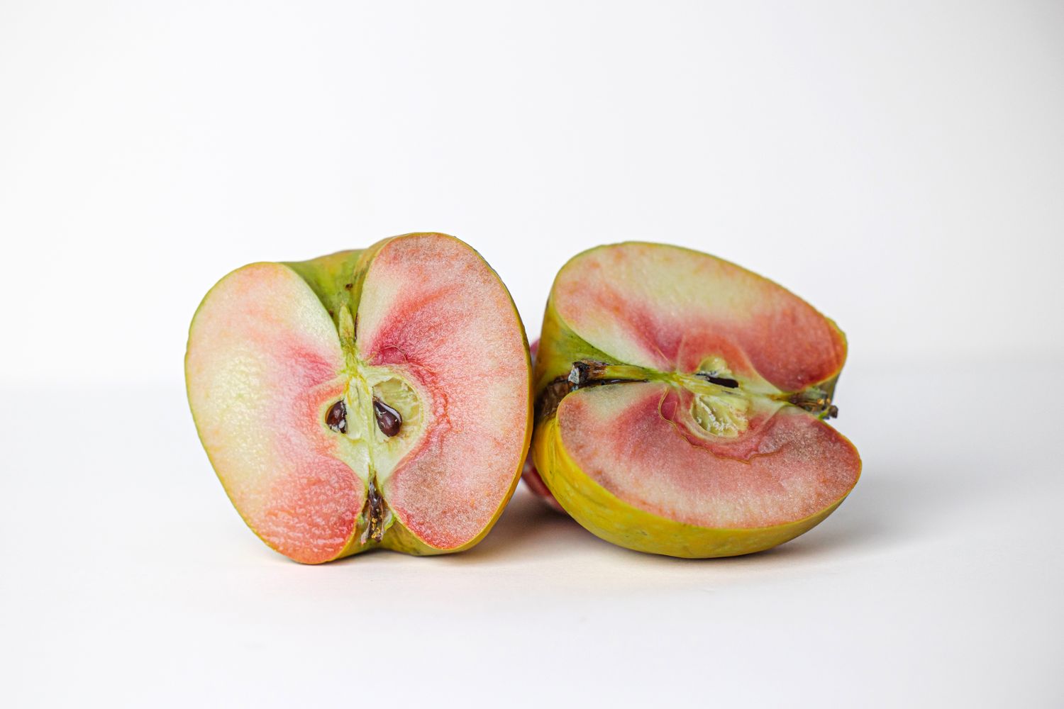 Two halves a single lucy glo apple on a white background.