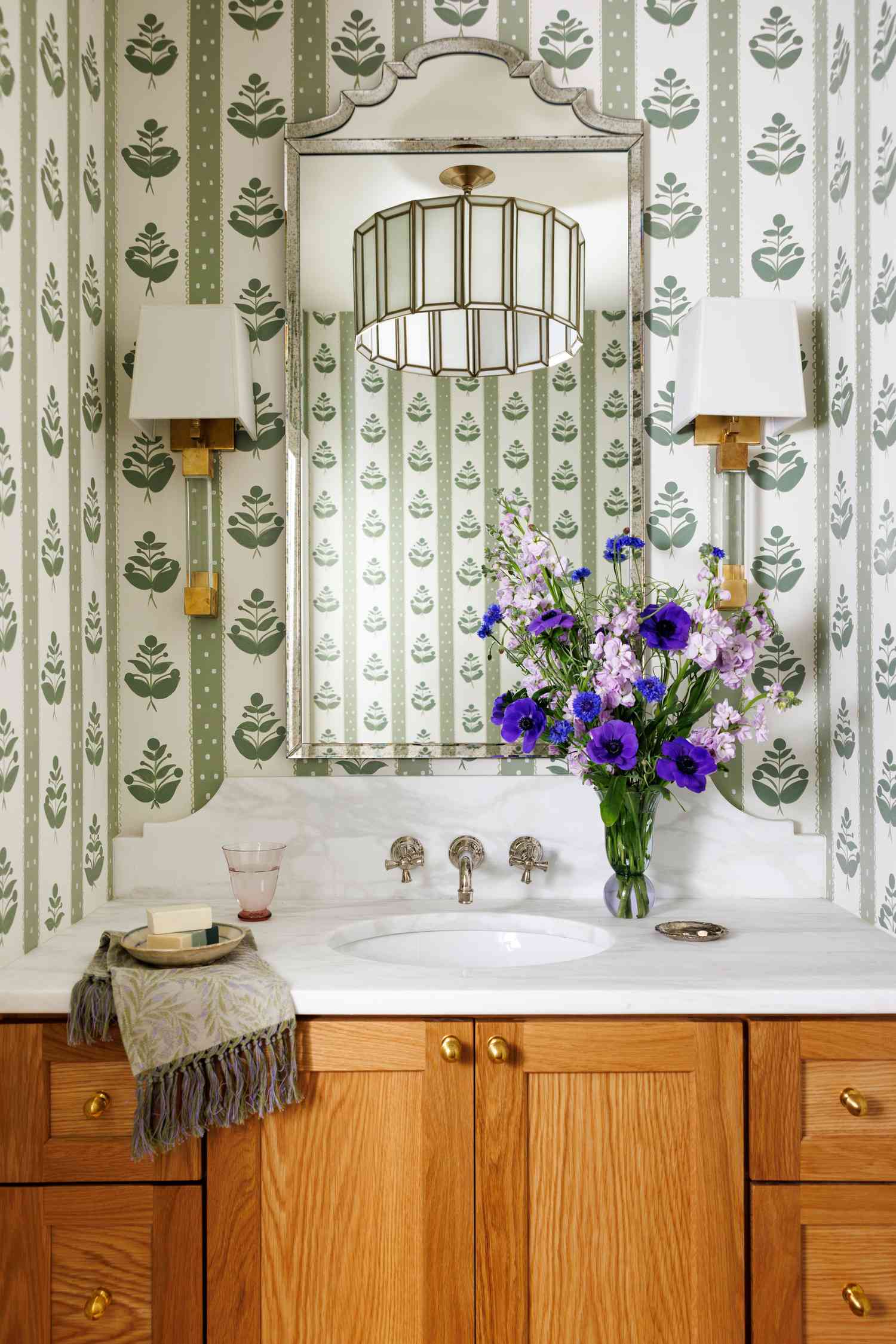 a white oak and marble sink vanity in a powder bath with green hand-painted wallpaper