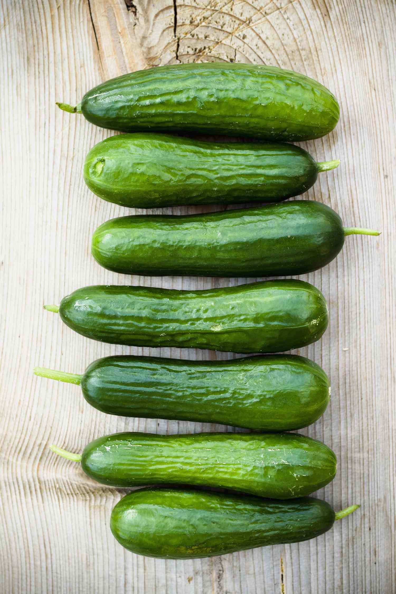 Eight cucumbers arranged on a wooden surface