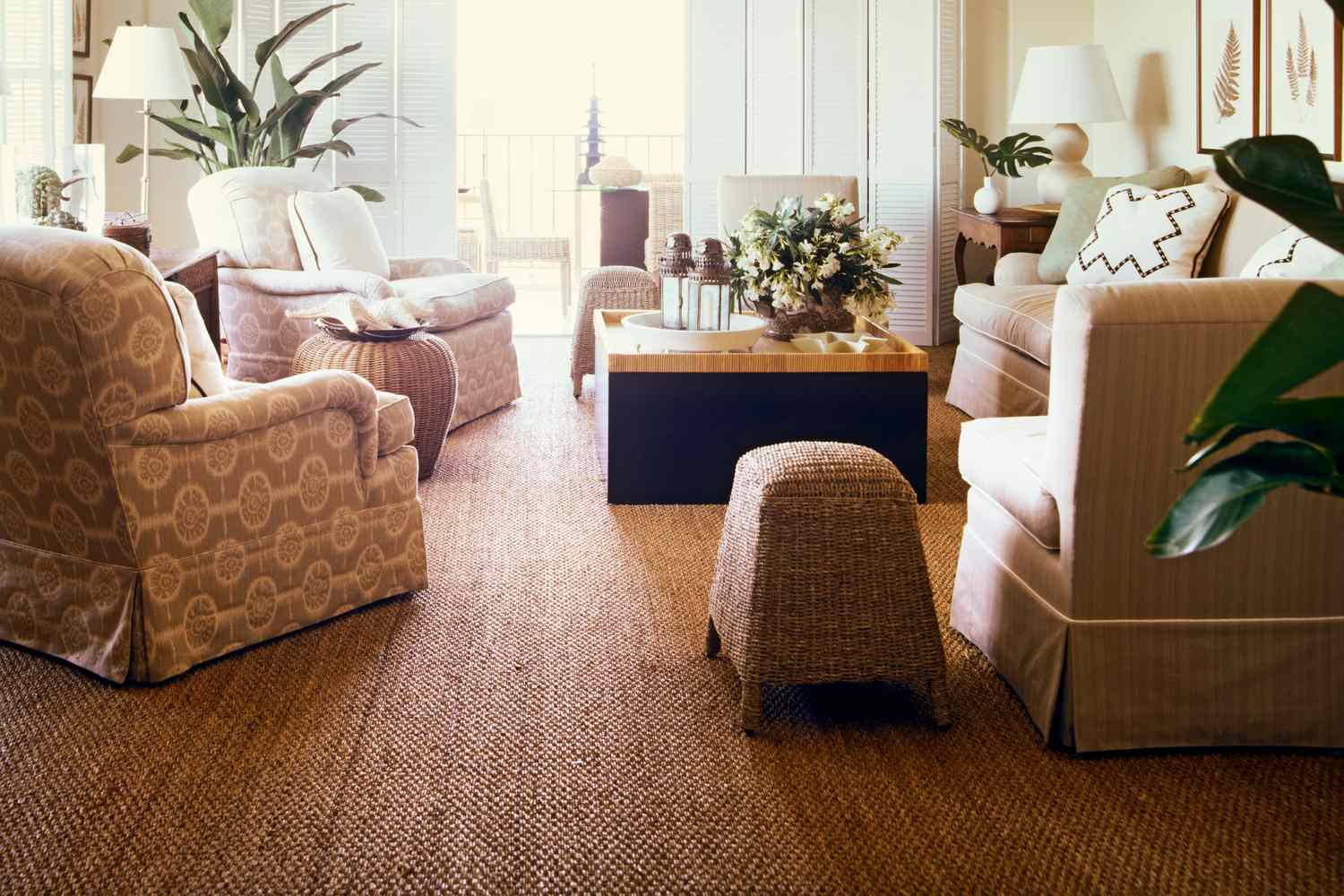 Living room with woven rug chairs plants and a central wooden coffee table