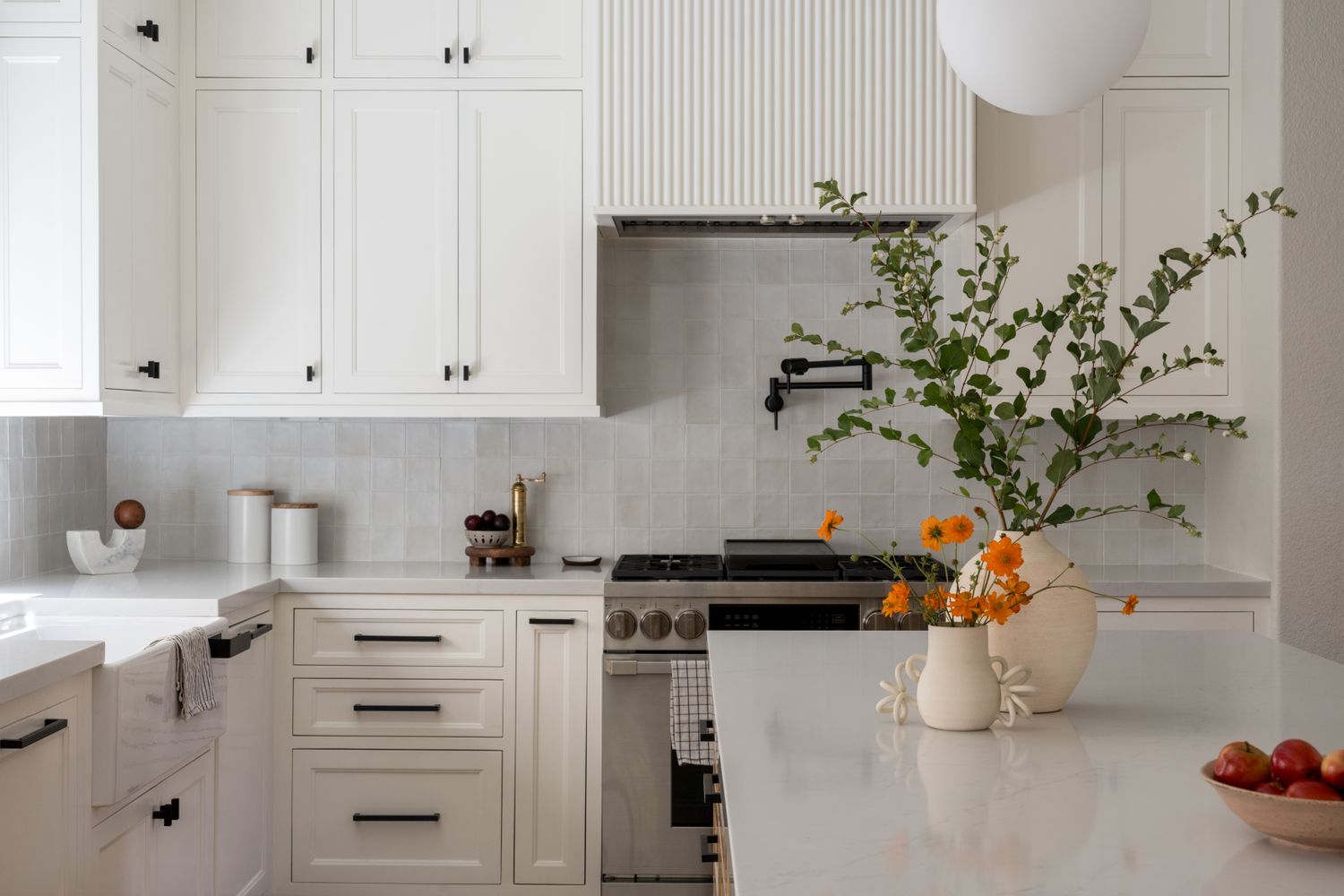 Modern kitchen design with white cabinetry, a large island, and decorative vases with flowers