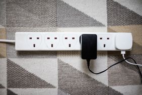 A power strip with plugs and adapters on a patterned rug