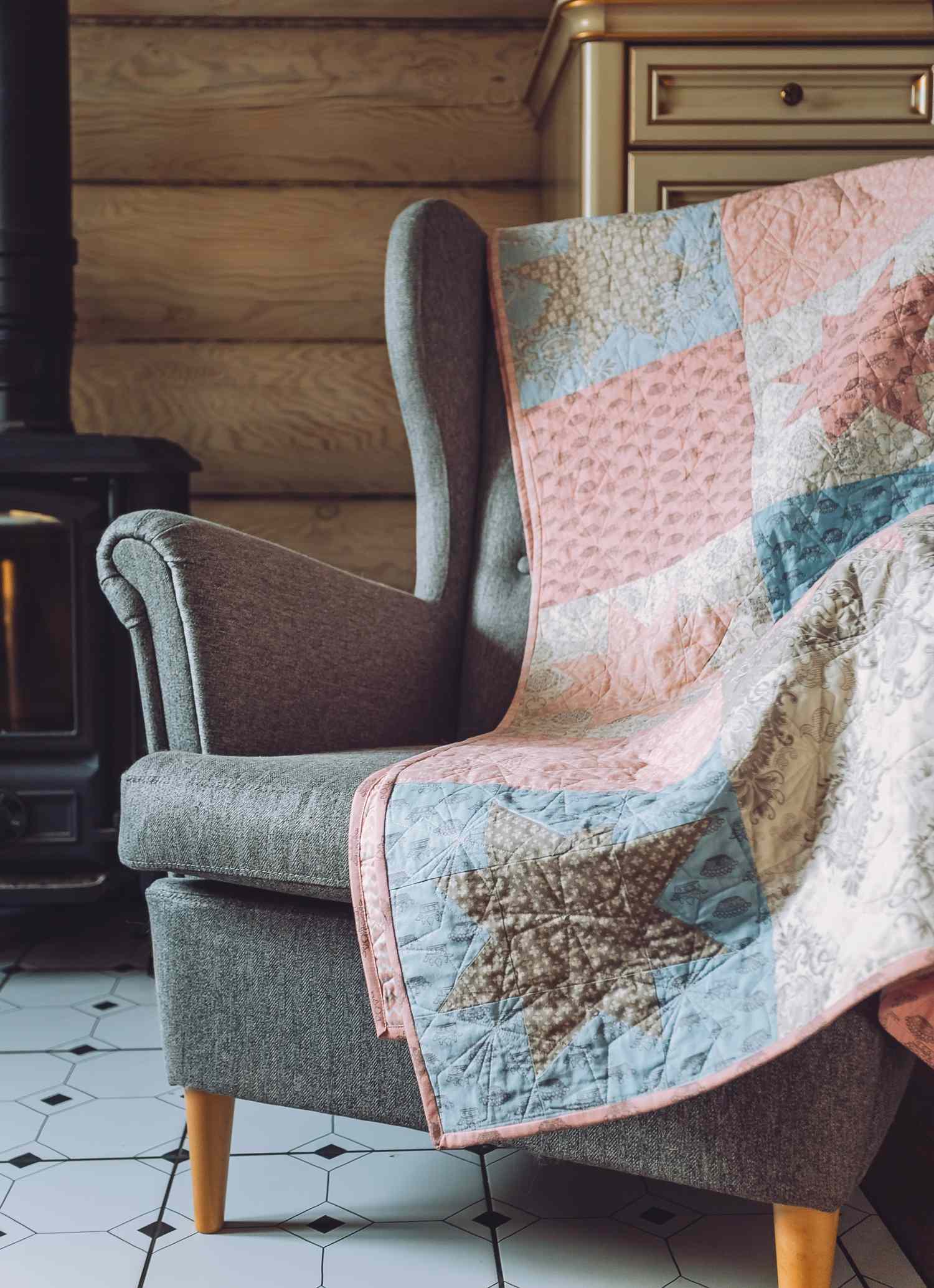 An armchair with a colorful quilt draped over it situated in a cozy room