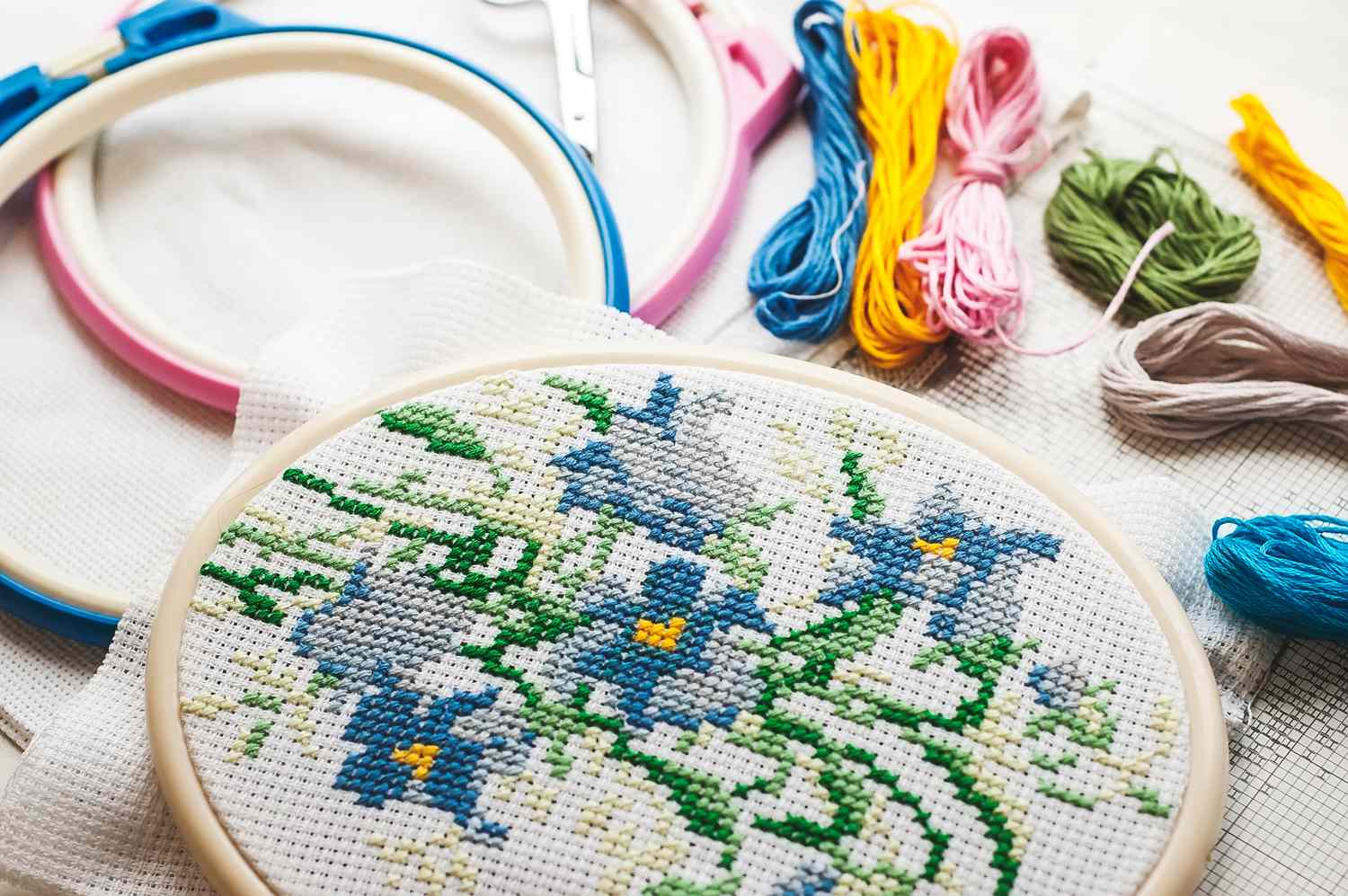 Embroidery in a hoop featuring a floral pattern with embroidery threads and tools nearby