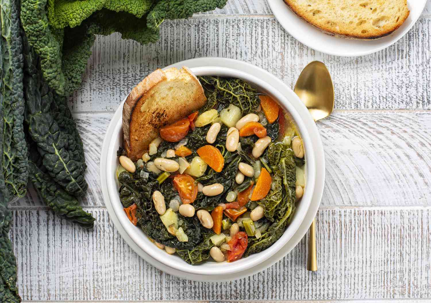 Tuscan soup with white beans kale in a bowl on textured surface