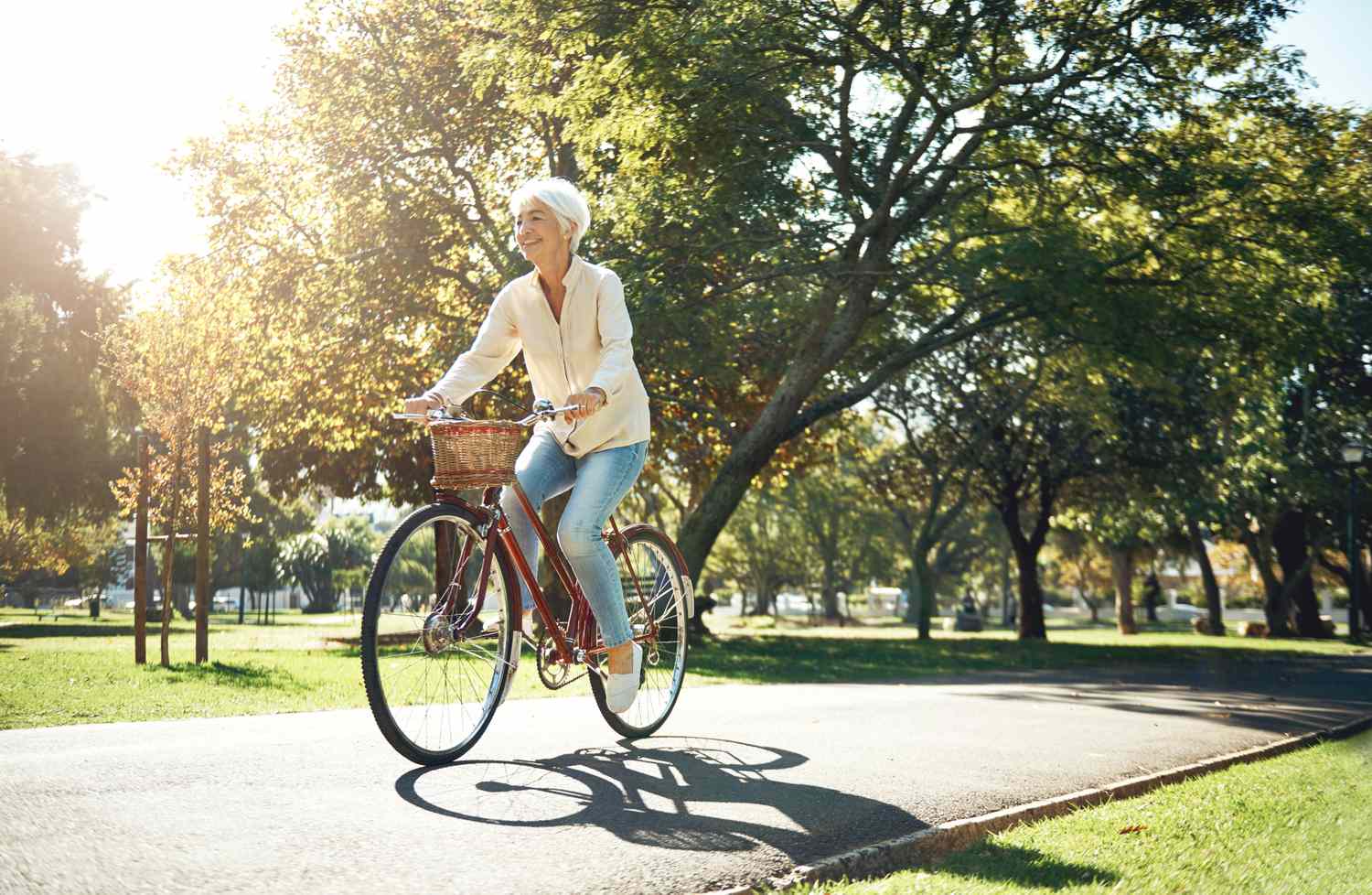 A person riding a bicycle on a path in a park surrounded by trees