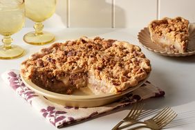 apple pie with piece removed, forks and drinks in background