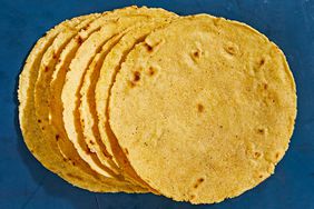 homemade corn tortillas stacked against blue background