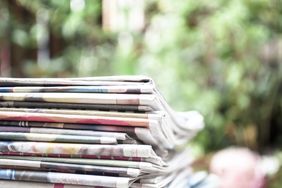 Newspapers folded and stacked on the table with garden or green background. Closeup newspaper and selective focus image. Time to read concept.