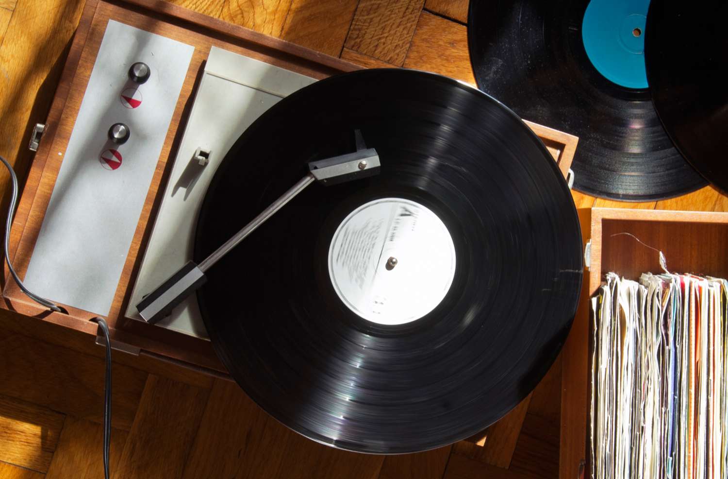 A vinyl record spinning on a turntable with a stack of records nearby