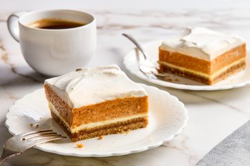 Slices of pumpkin mousse cheesecake on plates with a fork coffee cup in the background